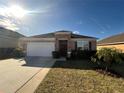 Front view of a one-story house with a garage and landscaping at 1038 Suffragette Cir, Haines City, FL 33844