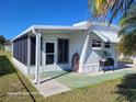 White manufactured home with screened porch and side yard at 1540 Skyview Ct, Lakeland, FL 33801