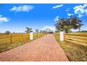 Long brick driveway leading to a farmhouse with a wood fence at 2200 Mcclellan Rd, Frostproof, FL 33843