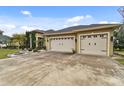 Tan house exterior with three-car garage and landscaped yard at 2774 Verandah Vue Way, Lakeland, FL 33812