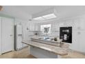 White kitchen with granite island, stainless steel appliances, and view into dining area at 3221 Pebble Bend Dr, Lakeland, FL 33810