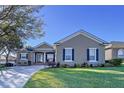 One-story house with a tan exterior, dark shutters, and a well-maintained lawn at 5825 High Ridge Loop, Lakeland, FL 33812