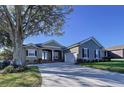 Tan house with dark shutters, landscaping, and a large driveway at 5825 High Ridge Loop, Lakeland, FL 33812