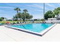 Community swimming pool with clear blue water surrounded by lounge chairs and mature palm trees at 6087 Southern Oaks Se Dr, Winter Haven, FL 33884