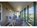 Rustic screened porch features rocking chairs and serene landscape views at 7275 Lake Hendry Rd, Fort Meade, FL 33841