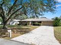 Single story home with a large driveway and mature tree at 2004 Varner Cir, Winter Haven, FL 33884