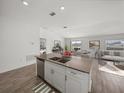 Modern kitchen featuring an island with a stainless steel sink and eat-in counter, connecting to the living area at 34575 Shellback St, Leesburg, FL 34788