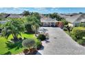 An elevated view of the property surrounded by manicured landscaping and a brick paved driveway at 751 Meandering Way, Polk City, FL 33868