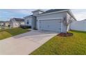 Gray house with a two-car garage and driveway, surrounded by a manicured lawn at 252 Walkers Point Dr, Auburndale, FL 33823