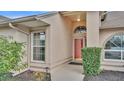 Front entrance features an arched window, a bright red door, and manicured shrubbery at 6244 Napa Dr, Lakeland, FL 33813