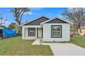 Charming single-story home with white stucco and black trim, featuring a well-maintained front lawn and a modern design at 105 3Rd Eloise St, Winter Haven, FL 33880