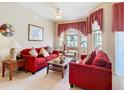 Inviting living room with neutral walls, plush red sofas, decorative pillows and bright, airy windows at 205 Terrace Ridge Cir # 205, Davenport, FL 33896
