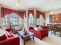 Comfortable living room with plush red sofas, decorative pillows, and natural light from large windows at 205 Terrace Ridge Cir # 205, Davenport, FL 33896