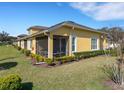 View of the yellow stucco house with a screened lanai and landscaped yard at 3019 Mission Lakes Dr, Lakeland, FL 33803
