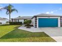 A well-kept single-Gathering home featuring a blue garage door and green lawn at 3719 Imperial Dr, Winter Haven, FL 33880