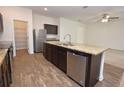 Open kitchen with stainless steel appliances, an island with a sink, and wood-look flooring at 4932 St James St, Winter Haven, FL 33881