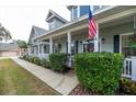 Inviting front porch with white columns, lush landscaping, and a charming American flag at 5155 Lake Deeson Woods Ct, Lakeland, FL 33805