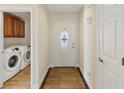 A welcoming foyer features wood-look tile flooring, a decorative front door, and a laundry room at 6610 Crescent Loop, Winter Haven, FL 33884