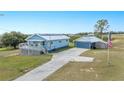 Charming blue home with solar panels and detached garage situated on expansive lawn with American flag at 705 Lake Ada Blvd, Dundee, FL 33838
