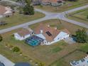 Aerial view of a home with white exterior, brown roof, detached garage and pool with screen enclosure at 1301 Hidden Creek Ct, Winter Haven, FL 33880