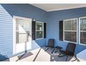 Cozy front porch with seating, light blue siding, and black window shutters at 140 Jackson Park Ave, Davenport, FL 33897