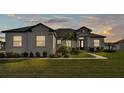 Beautiful one-story home at dusk with a well-manicured lawn, a stone accent entryway, and decorative landscaping at 2985 Pickards Pass, Lakeland, FL 33813