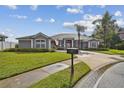 Charming one-story home with a well-manicured lawn, palm trees, and a driveway leading to a two-car garage at 335 Osprey Landing Way, Lakeland, FL 33813