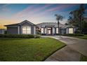 Charming one-story home with a well-manicured lawn, palm trees, and a driveway leading to a two-car garage at 335 Osprey Landing Way, Lakeland, FL 33813