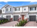 Charming townhome exterior with a gray garage door, brick driveway, and well-manicured landscaping at 5002 Rain Shadow Dr, St Cloud, FL 34772