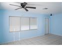 Bright living room with neutral tile floors, a ceiling fan, and ample natural light from multiple windows at 526 Hampton Ave, Lakeland, FL 33801