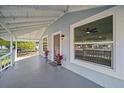 Covered front porch featuring neutral paint, potted plants, large windows and a ceiling fan at 602 E Orange St, Auburndale, FL 33823