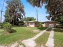 View of the home's exterior showcasing the driveway leading to a detached garage and mature trees at 116 S Lanier Ave, Fort Meade, FL 33841