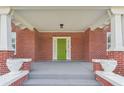 Covered front porch featuring red brick, columns, and a bright green front door at 1539 E Fern Rd, Lakeland, FL 33801