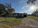 Inviting one-story house with an attached garage and a gravel driveway under a sunny blue sky at 1560 Imperial Ave, Bartow, FL 33830