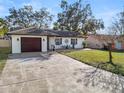Quaint single-story home with a large driveway and minimalist landscaping at 327 Corona Del Mar St, Lakeland, FL 33809