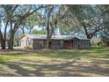 Rustic home featuring wood siding, a metal roof, inviting front porch, and a spacious, tree-shaded yard at 4075 Davis Rd, Mulberry, FL 33860