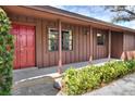 Charming home exterior with a red front door, wood siding and meticulously landscaped yard at 4613 Little Grove Ln, Lakeland, FL 33813