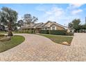 A single story home is enhanced by a circular brick driveway, lush landscaping, and brick and siding exterior at 4624 Kings Point Ct, Lakeland, FL 33813