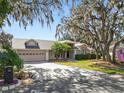 Charming single Gathering home featuring mature trees, well-manicured lawn, and a two-car garage at 7410 Locksley Ln, Lakeland, FL 33809