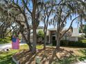 Charming single Gathering home featuring mature trees, well-manicured lawn, and an American flag at 7410 Locksley Ln, Lakeland, FL 33809