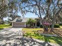 Charming single Gathering home featuring mature trees, well-manicured lawn, and a two-car garage at 7410 Locksley Ln, Lakeland, FL 33809