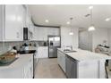 Modern kitchen features white cabinetry, stainless steel appliances, and a large center island, perfect for cooking and entertaining at 2027 Airedale Way, Lake Alfred, FL 33850