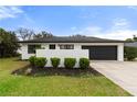 Charming single-story home with a black garage door, vibrant green lawn, and manicured shrubbery at 2326 Eastmeadows Rd, Lakeland, FL 33812