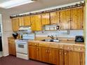 Functional kitchen featuring ample wood cabinets, a white range, and a stainless steel sink at 3023 Maplewood Ave, Lakeland, FL 33803