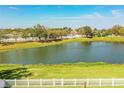 A scenic view of the backyard showing the lake view, landscaping, and fenced in yard at 3882 Rollingsford Cir, Lakeland, FL 33810