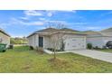 An exterior view of a single-story home with a well-manicured lawn, driveway, and tidy landscaping at 965 Eagle Rock Ter, Winter Haven, FL 33880