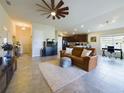Spacious open-concept living room with tile flooring, fan and comfortable seating area in a neutral color palette at 1134 Legatto Loop, Dundee, FL 33838