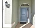Close-up of a stylish blue front door with sidelight window and decorative transom window at 136 Krenson Bay Loop, Winter Haven, FL 33881