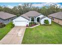 Charming single-story home featuring well-manicured lawn, lush landscaping, and a paved driveway leading to an attached garage at 153 Heritage Park Ln, Mulberry, FL 33860