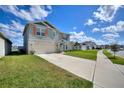 Two-story home with stone accents, two-car garage, well-manicured lawn, and neutral colored facade at 421 Chayne Pl, St Cloud, FL 34771